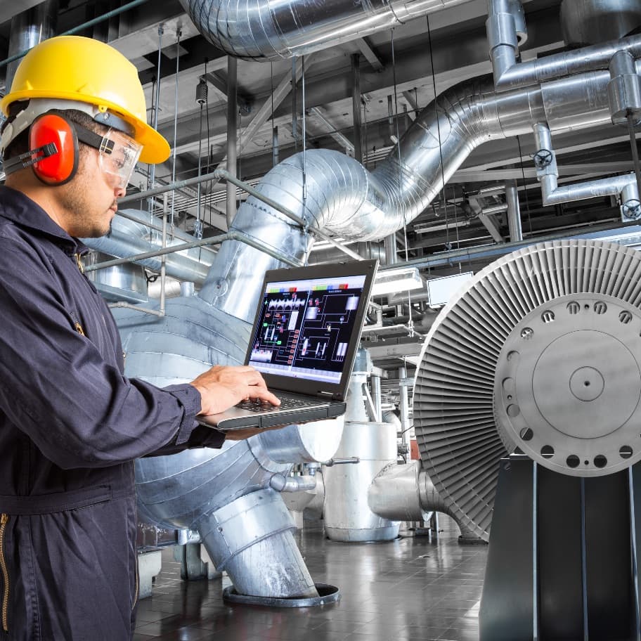 Trabajador analizando datos en su computadora de una maquinaria industrial en México